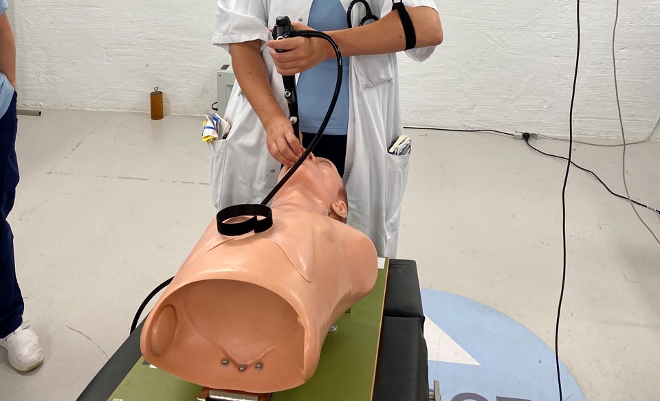 Kvinde står med tube indsat i træningsdukkes mund