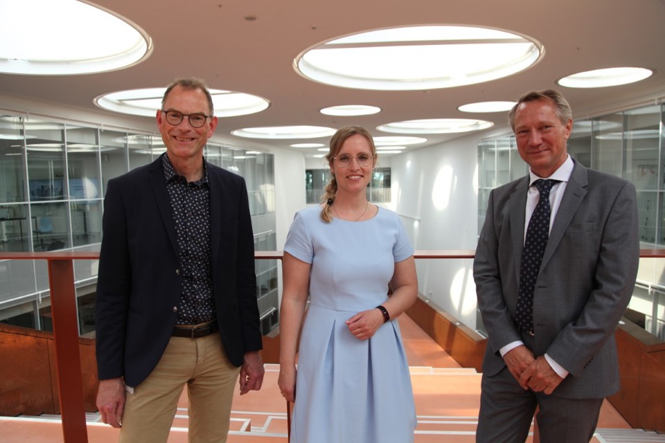 Tre mennesker, to mænd og en kvinde, smiler til kameraet